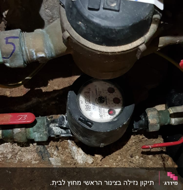 מונה מים עם צינורות וברזים אדומים